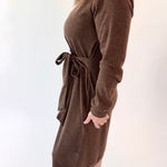 Woman wearing a brown dress with a belt against a white background