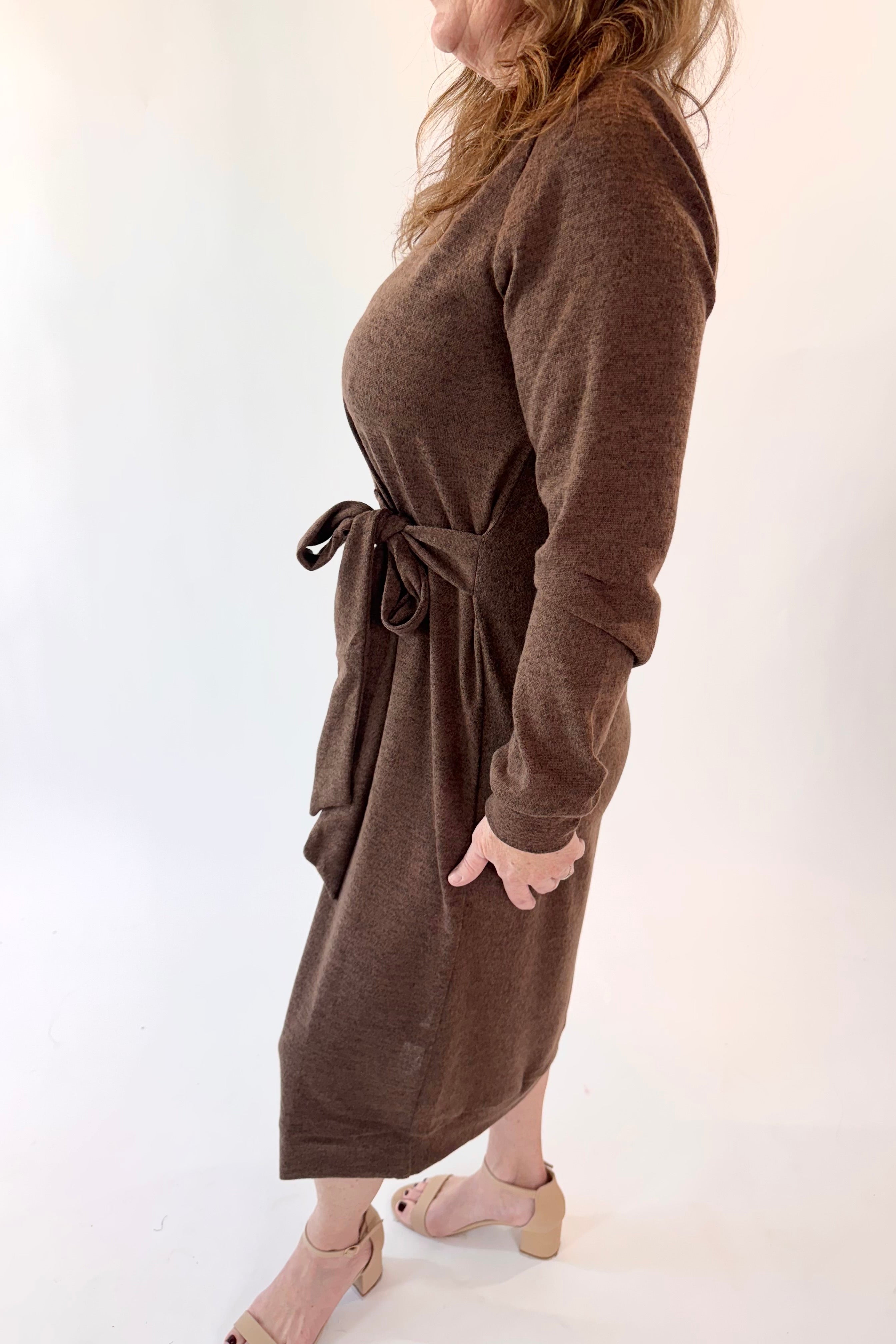 Woman wearing a brown dress with a belt against a white background