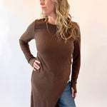 Woman wearing a brown long-sleeve top and blue jeans on a white background