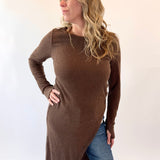 Woman wearing a brown long-sleeve top and blue jeans on a white background