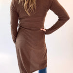 Person wearing a brown ribbed dress with a belt on a white background