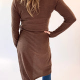 Person wearing a brown ribbed dress with a belt on a white background