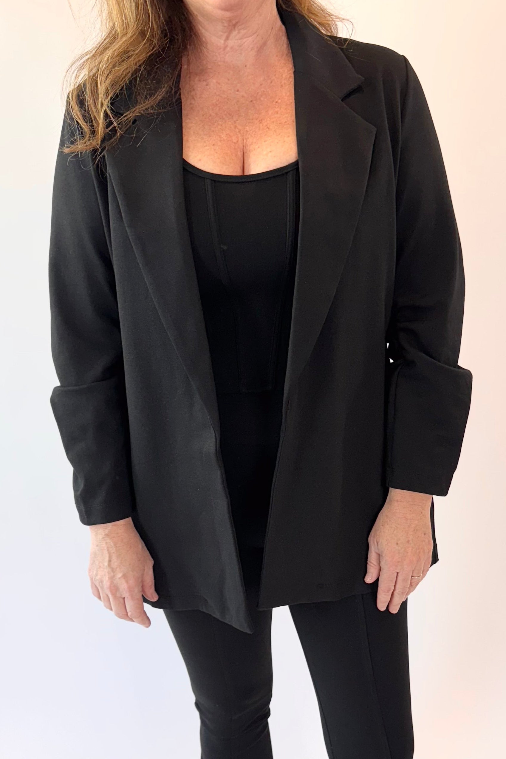Woman wearing a black blazer and pants on a white background