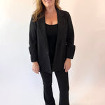 Woman wearing a black suit standing against a white background