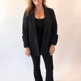 Woman wearing a black suit standing against a white background