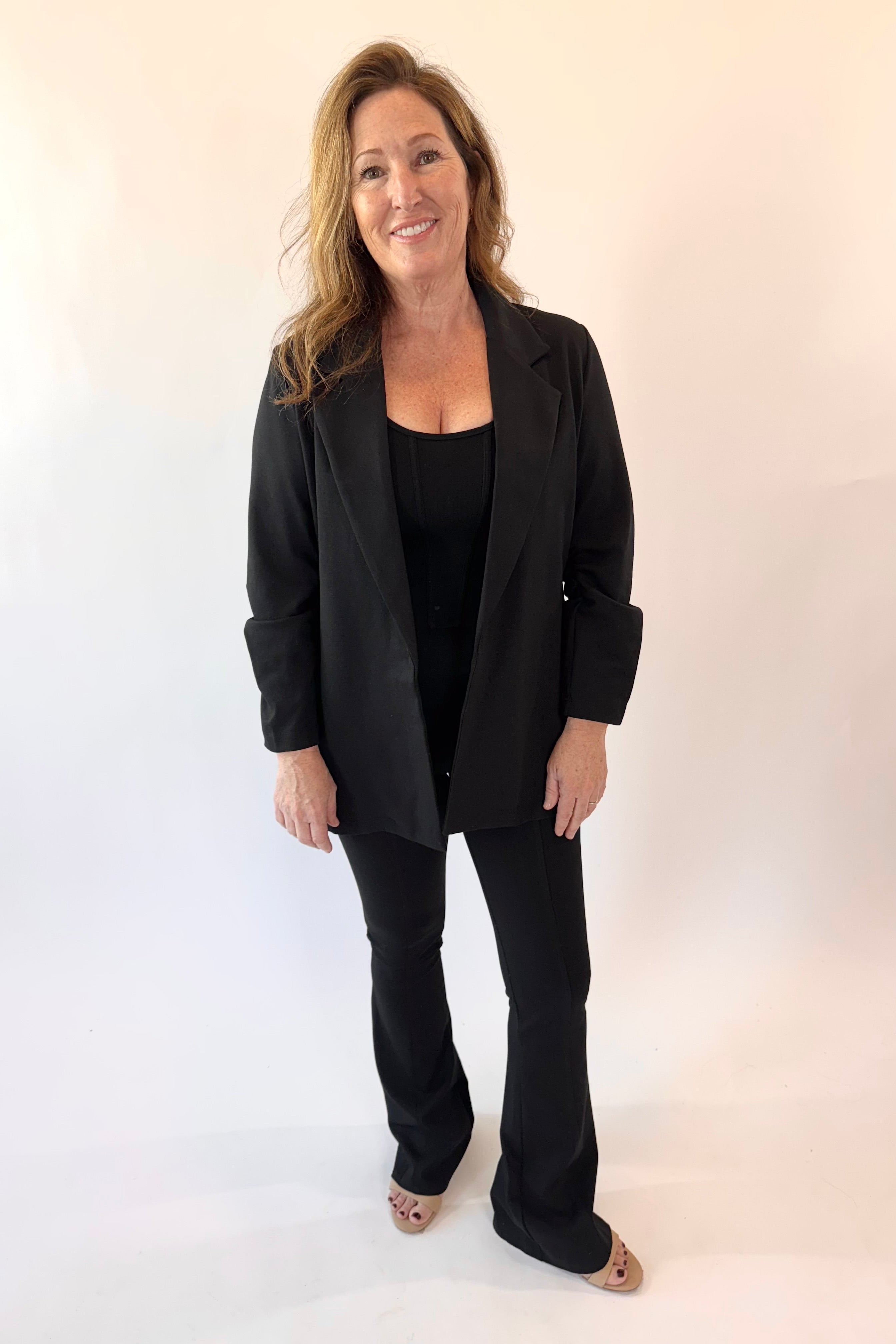Woman wearing a black suit standing against a white background