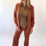 Woman wearing a brown suit standing against a white background