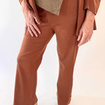 Person wearing a brown outfit with wide-leg pants on a white background