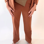 Person wearing a brown outfit with a beige top and pants on a white background