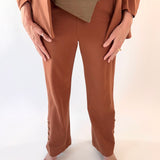 Person wearing a brown outfit with a beige top and pants on a white background