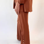 Person wearing a brown suit with wide-leg pants on a white background