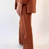 Person wearing a brown suit with wide-leg pants on a white background