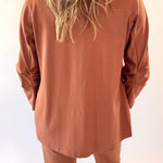 Person wearing a brown outfit with long sleeves and pants against a light background