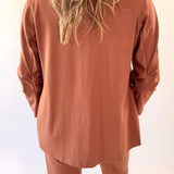 Person wearing a brown outfit with long sleeves and pants against a light background