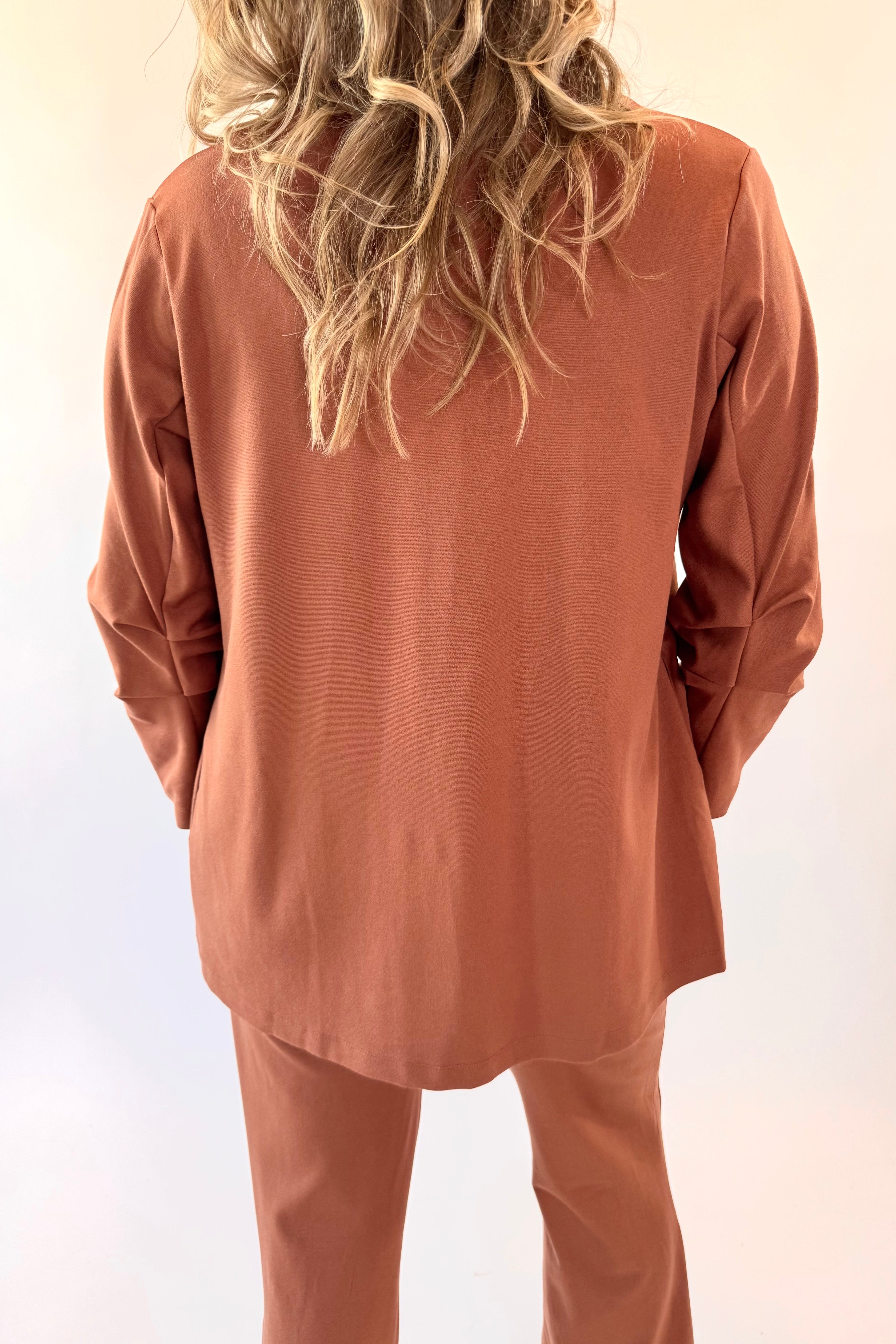 Person wearing a brown outfit with long sleeves and pants against a light background