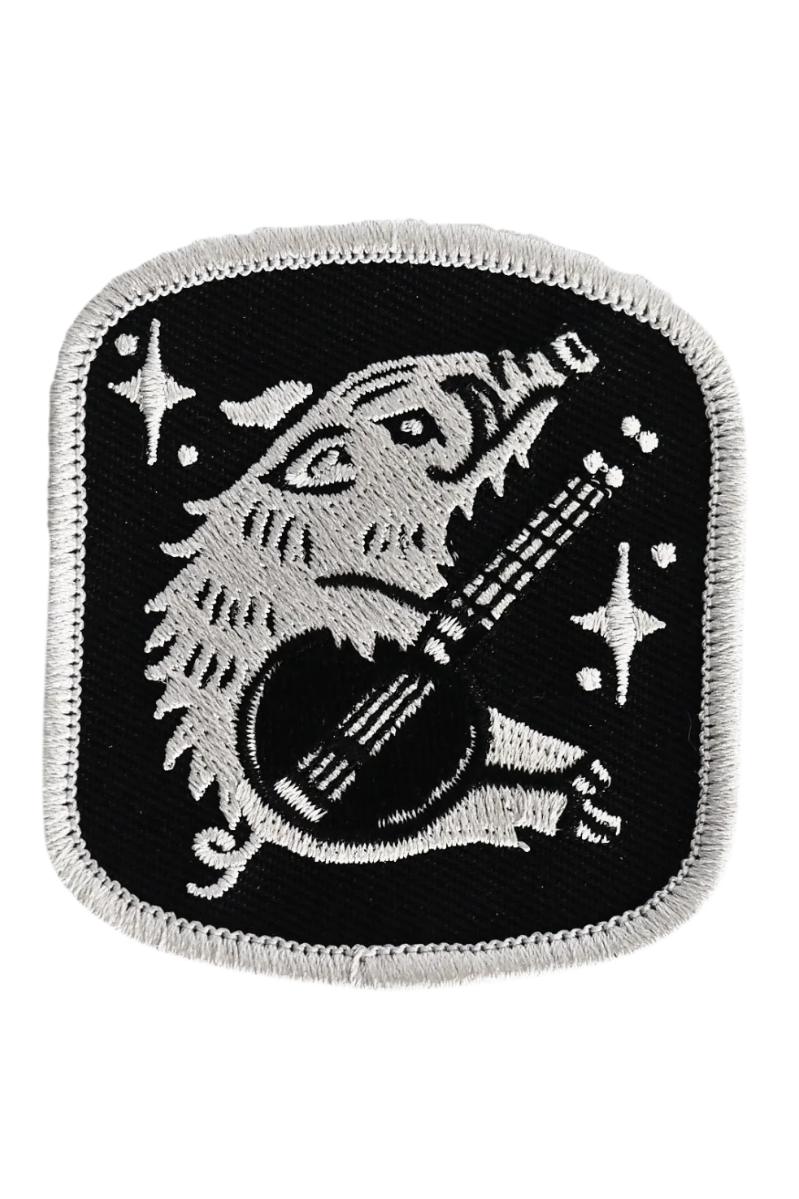Embroidered patch with a wolf playing a guitar on a black background