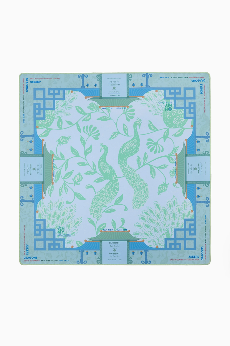 Decorative placemat with green floral design on a blue geometric border. Isla Mat in Tube | Oh My Mahjong