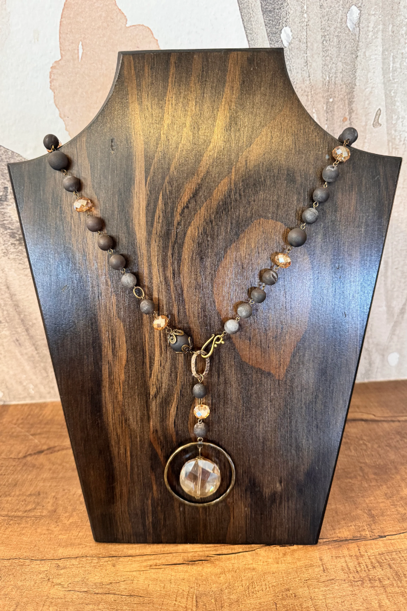 Necklace with beads on a wooden stand against a neutral background. Drusy Quartz Beaded Pendant Necklace – Charcoal &amp; Blush