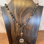 Necklace with beads on a wooden stand against a neutral background. Drusy Quartz Beaded Pendant Necklace – Charcoal &amp; Blush