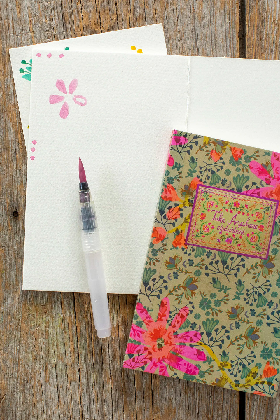 Floral notebook and pen on a wooden surface