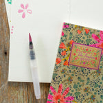 Floral notebook and pen on a wooden surface