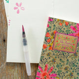 Floral notebook and pen on a wooden surface