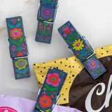 Colorful floral-patterned clips on a marble surface with a bag of chocolate in the background.
