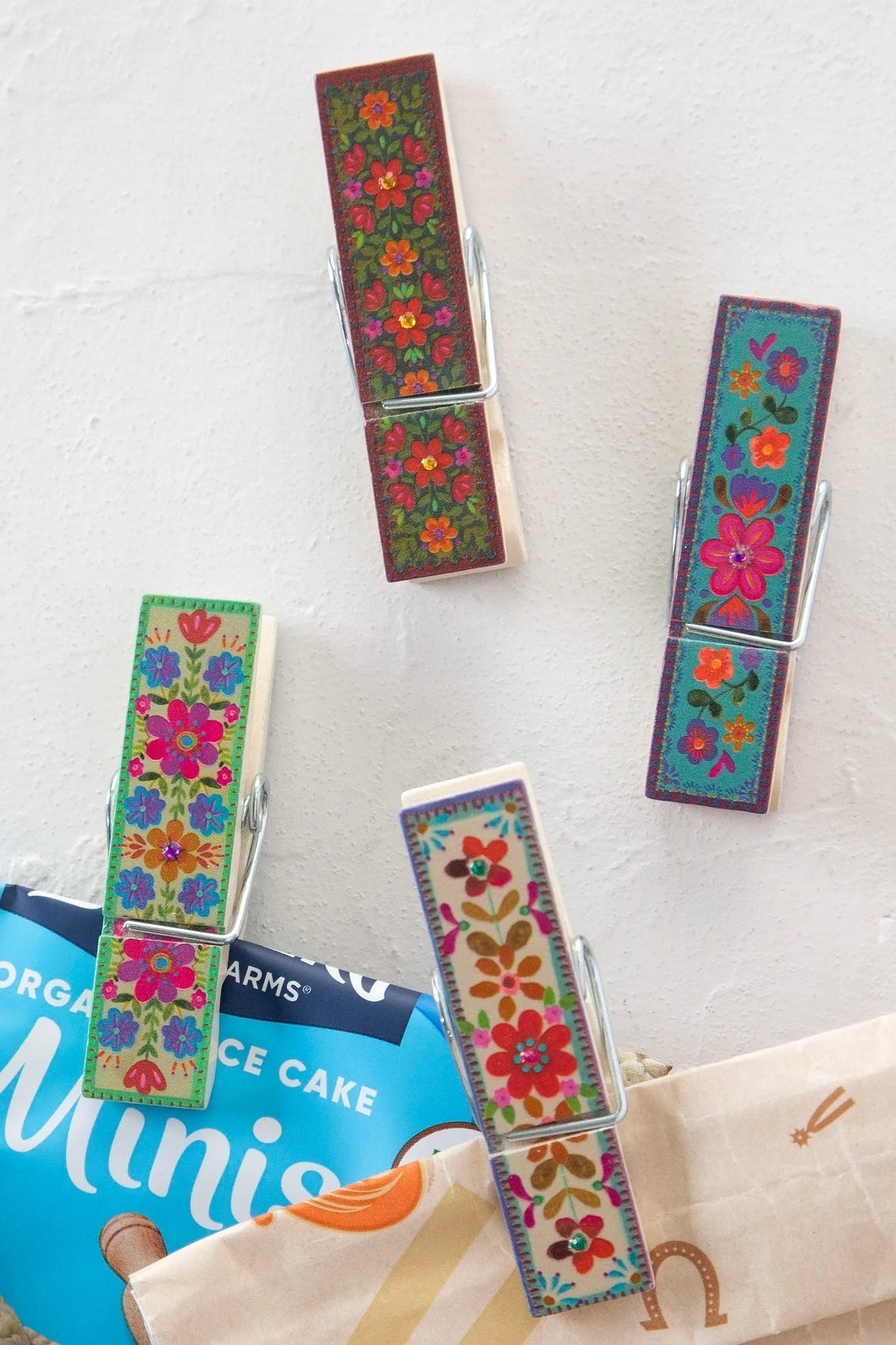 Colorful floral-patterned clothespins on a white surface with a package of ice cream in the background.
