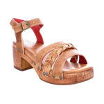 A tan-colored leather sandal with braided leather accents, metal studs, red leather lining, and a manageable heel height, displayed against a white background.