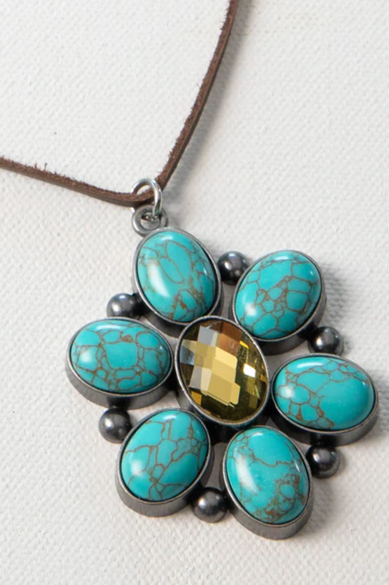 Necklace with turquoise stones and a central yellow gem on a white background