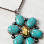 Necklace with turquoise stones and a central yellow gem on a white background