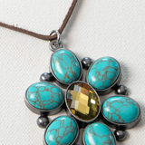 Necklace with turquoise stones and a central yellow gem on a white background
