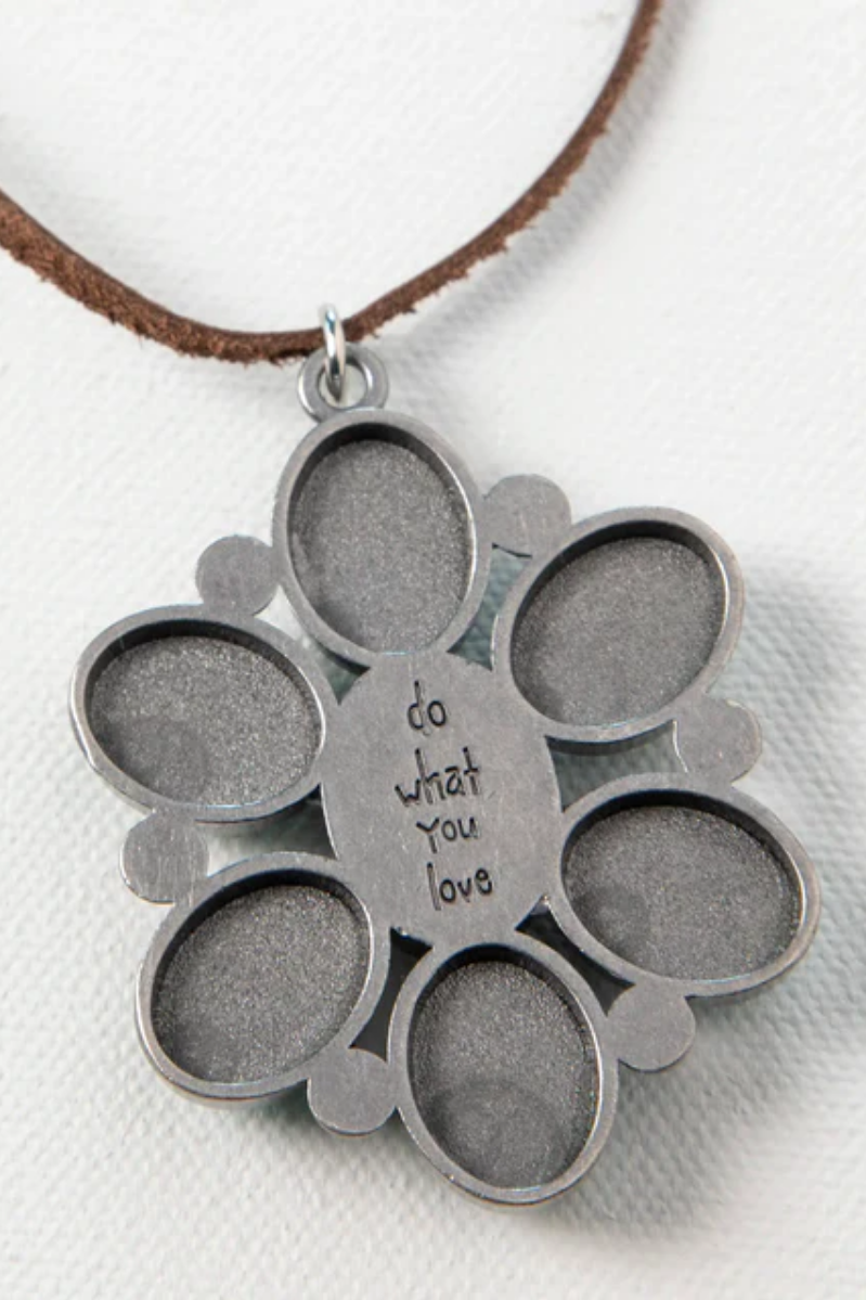 Silver pendant with circular cutouts and 'do what you love' engraving on a white background
