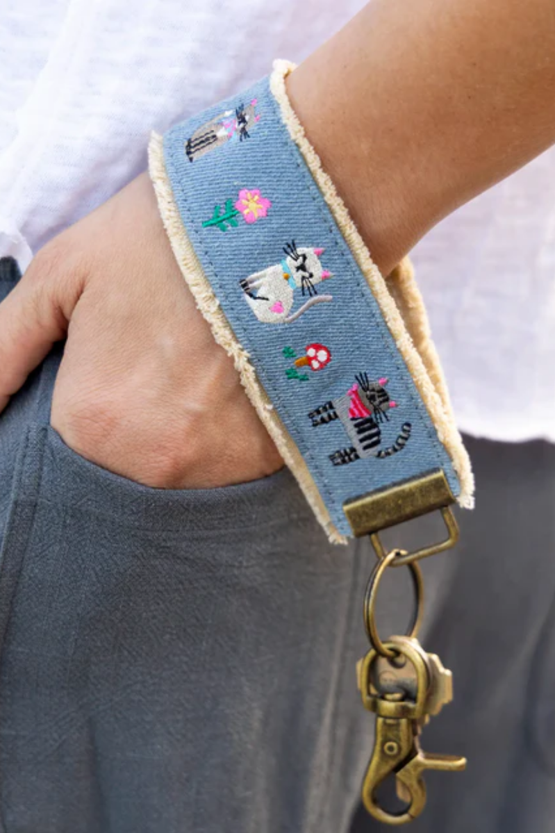 Wristlet with cat design and gold clasp worn on wrist