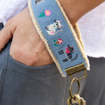 Wristlet with cat design and gold clasp worn on wrist