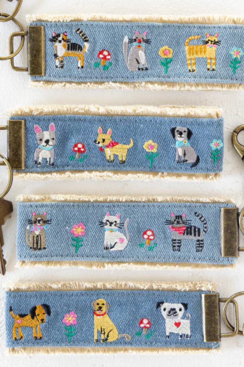 Set of denim keychains with embroidered animal designs on a white background