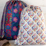 Two floral-patterned drawstring bags on a white surface with a brick wall background.