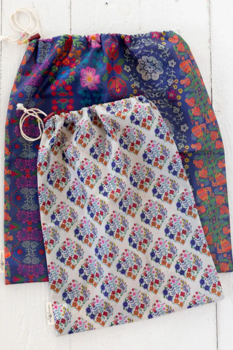 Two drawstring bags with floral patterns on a white wooden surface