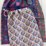 Two drawstring bags with floral patterns on a white wooden surface