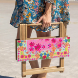 Person holding a floral-patterned folding chair on a beach