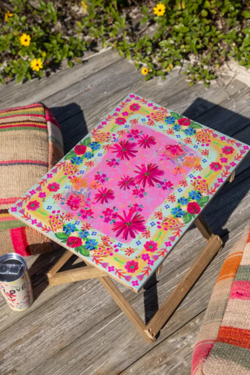 Colorful floral-patterned stool on a wooden deck with a can of soda.