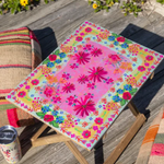 Colorful floral-patterned stool on a wooden deck with a can of soda.