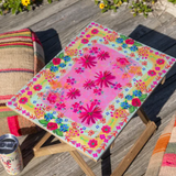 Colorful floral-patterned stool on a wooden deck with a can of soda.