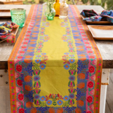 Colorful floral-patterned table runner on a wooden table with a blurred outdoor background.