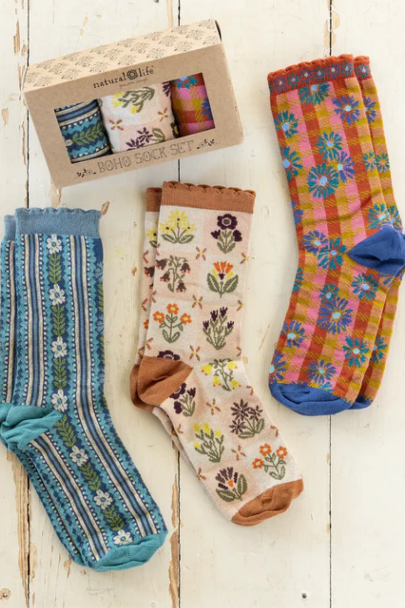 Set of colorful patterned socks on a wooden surface with a gift box.