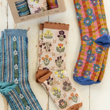 Set of colorful patterned socks on a wooden surface with a gift box.