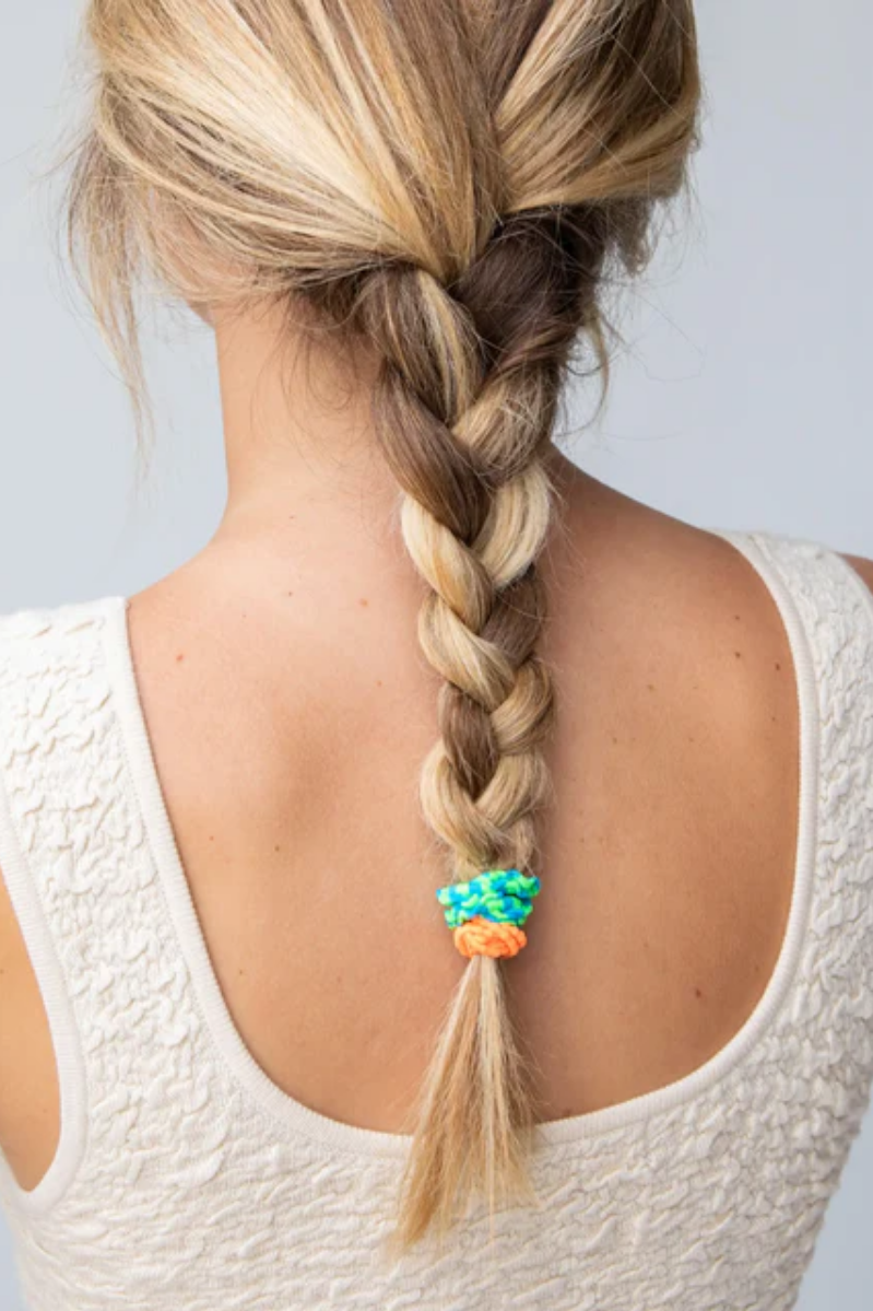 Braided hair with colorful beads on a plain background