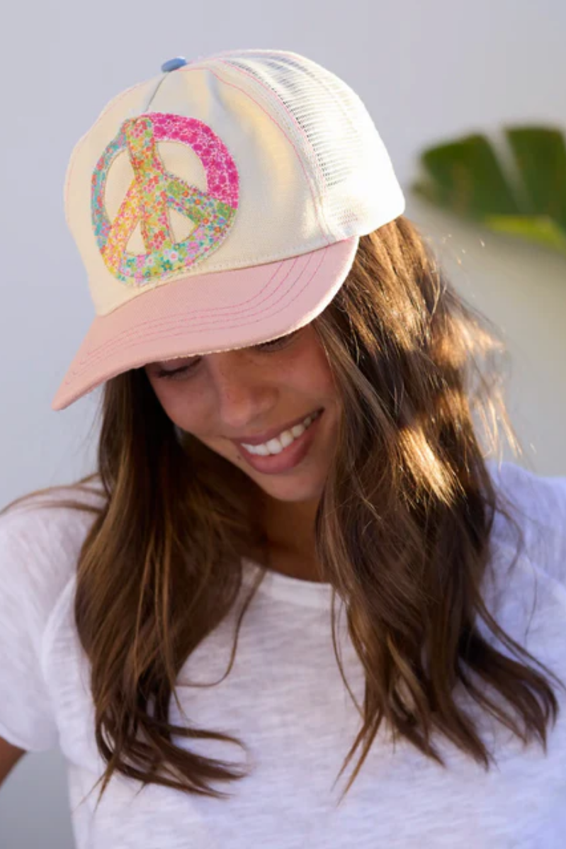 Woman wearing a colorful peace symbol cap with a white background