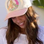 Woman wearing a colorful peace symbol cap with a white background