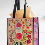 Floral-patterned tote bag with text held by a hand on a white background
